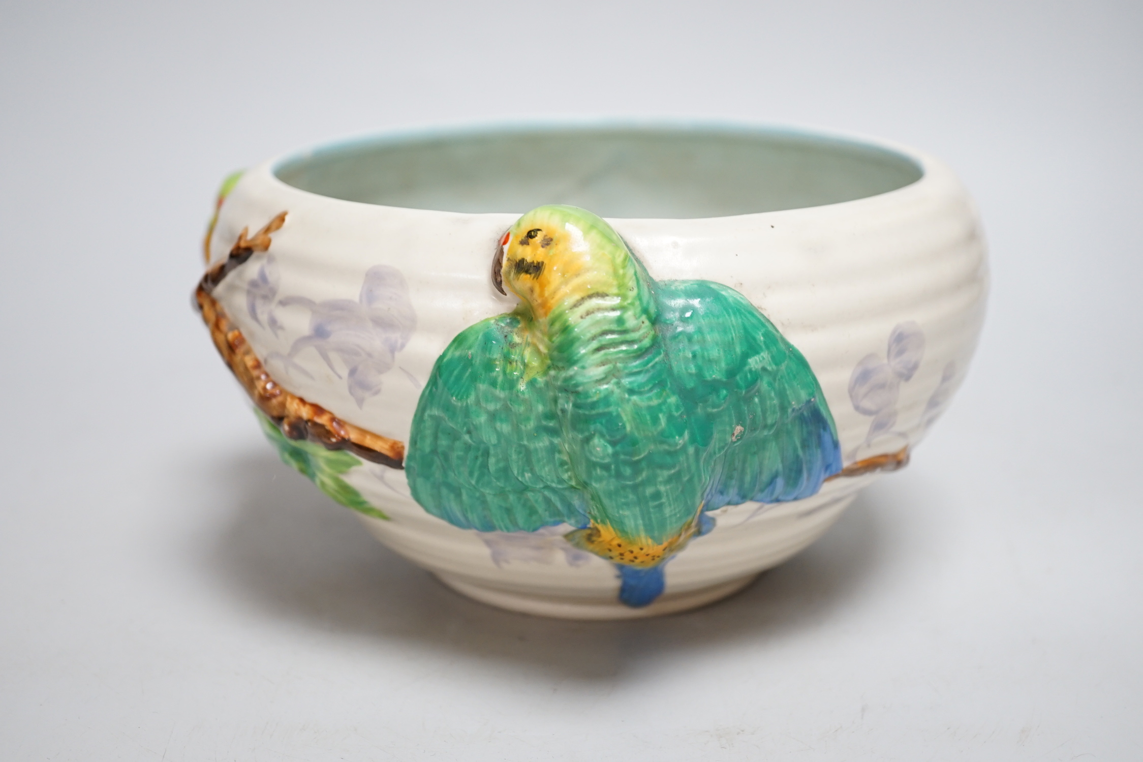 A late Clarice Cliff bowl with perched parrot decoration, 12cm tall